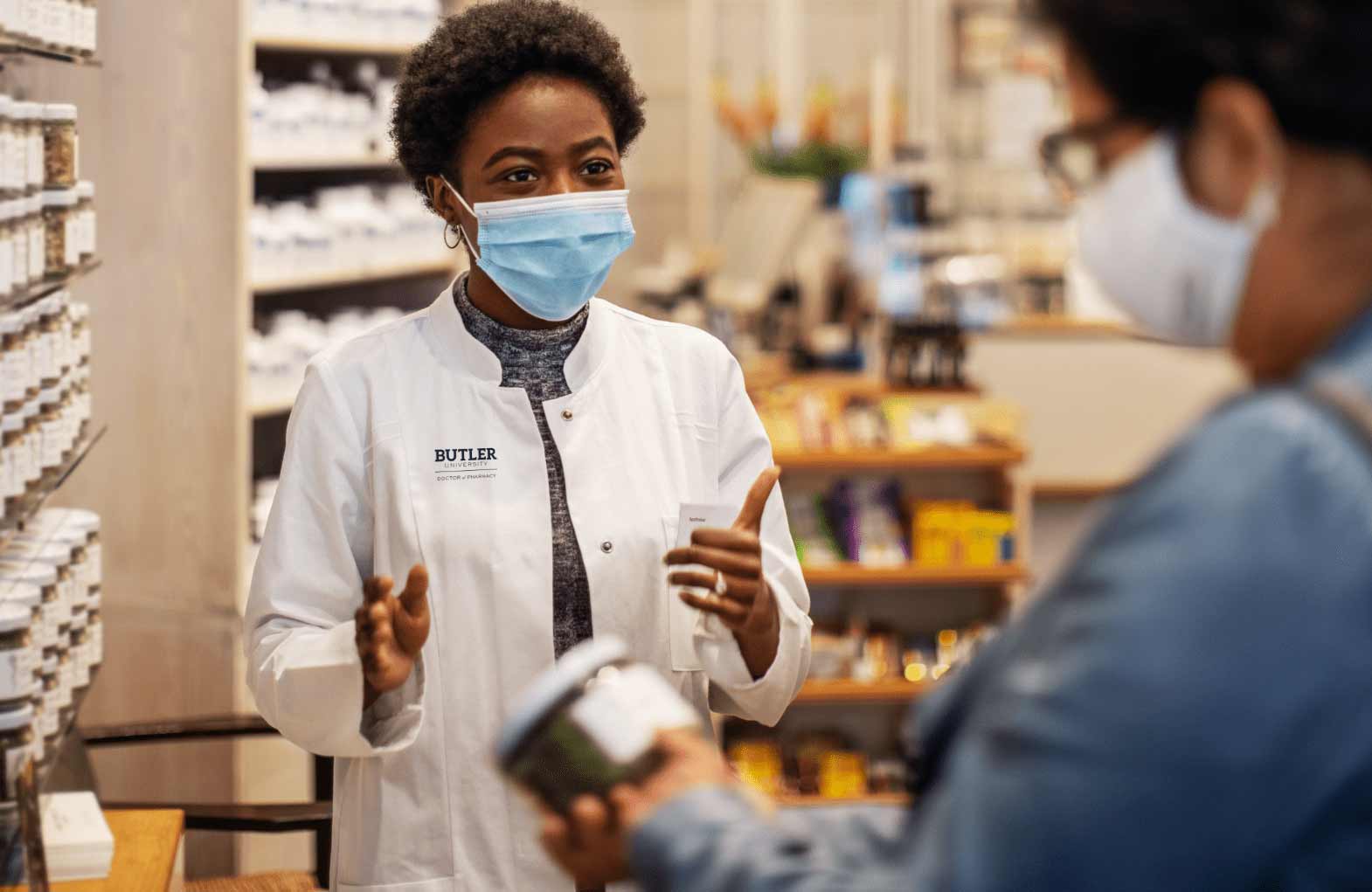 Butler student in mask assisting a customer at the pharmacy